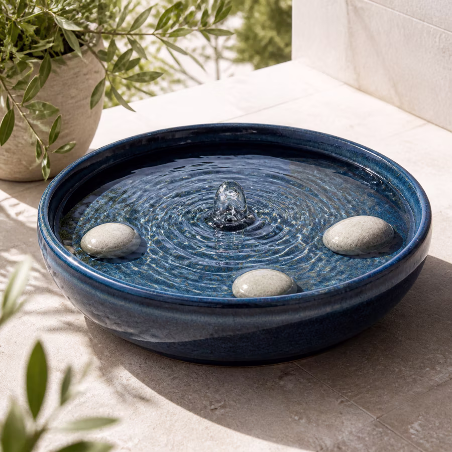 Blaue Keramikschale mit sprudelndem Wasser und hellen Steinen