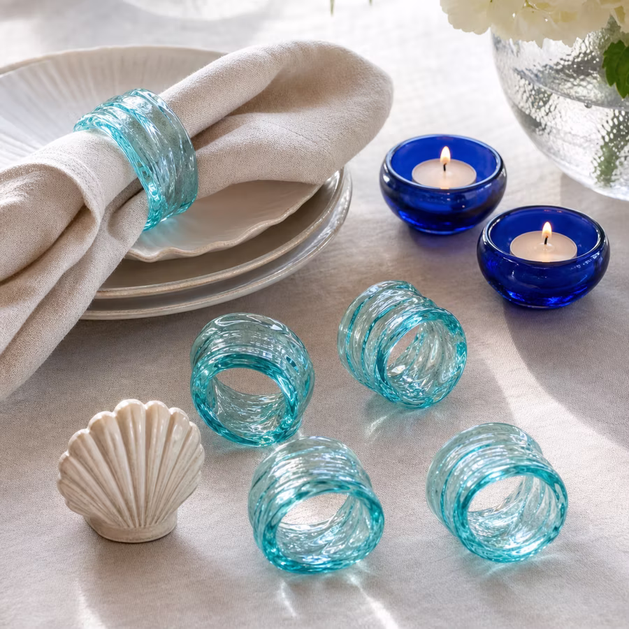 Transparente aqua-blaue Serviettenringe auf hellem Leinen